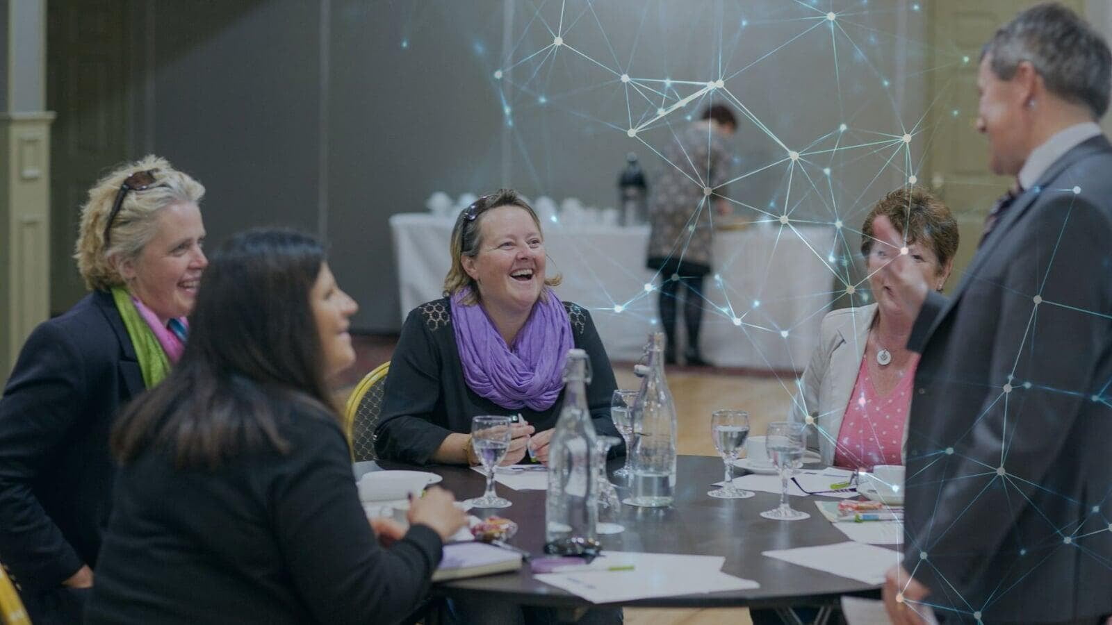 People gathered around a table at an event talking and laughing.